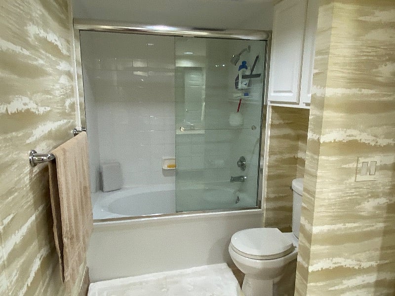 Shower/tub combo, additional cabinets above toilet.