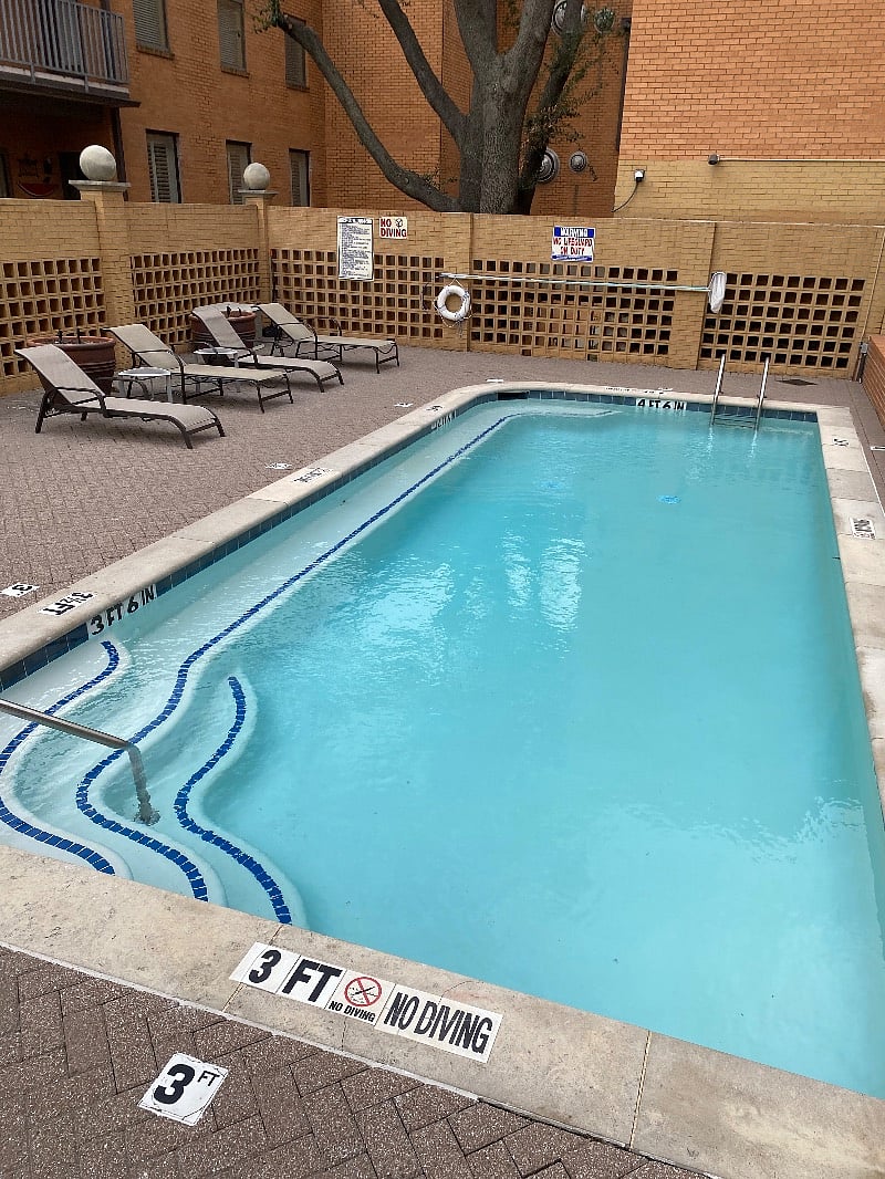 Outdoor pool and seating near grill.