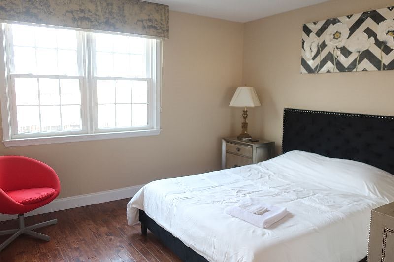 Front bedroom with queen size bed, filled with natural lighting.