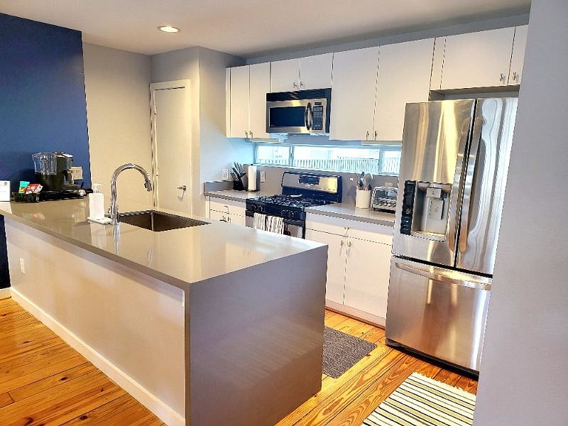Fully-equipped kitchen features stainless steel appliances and waterfall edge countertop