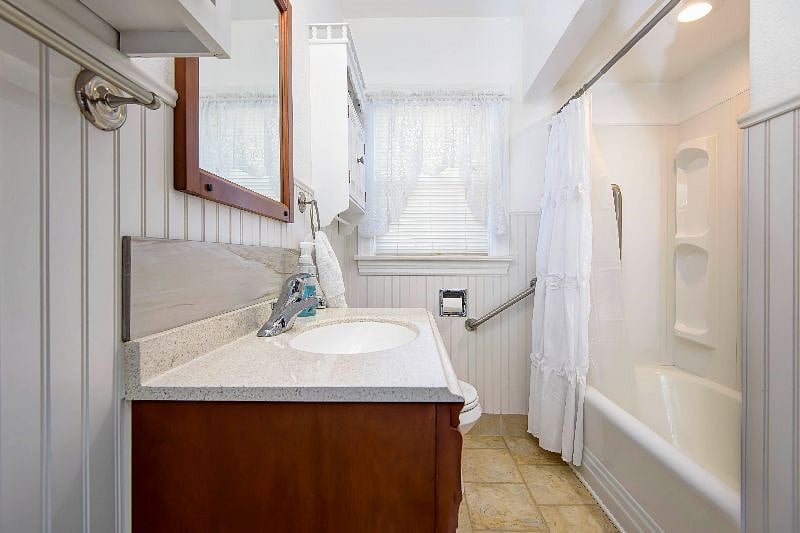 Bathroom with single vanity, shower/tub, and window.