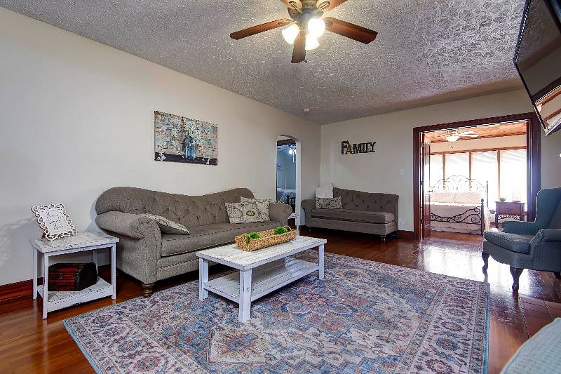 The large living room has two couches, a fireplace, flat screen television, a ceiling fan, and plenty of space.