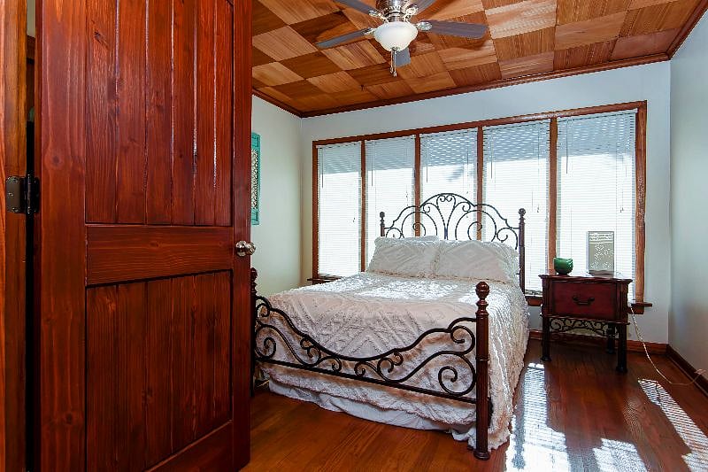 Bedroom 2 offers natural light, warm wood floors, and a ceiling fan.