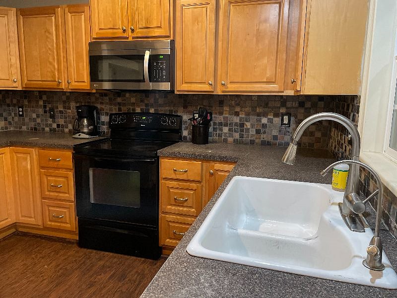 Kitchen with two-vat sink, spray nozzle, filtered water, oven with stove-top, microwave, coffee maker, dishes, utensils, pots and pans.