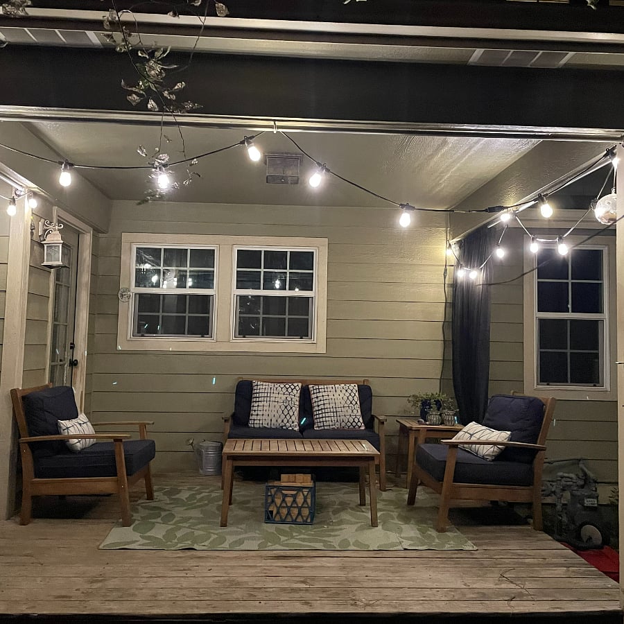Covered back deck with comfortable patio furniture and string lights.
