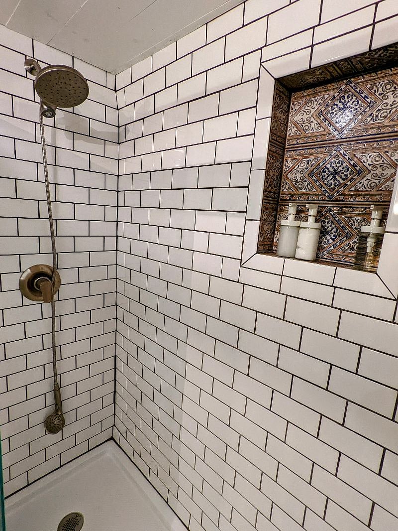 Subway-tiled full shower w/detachable head and unique tiled alcove