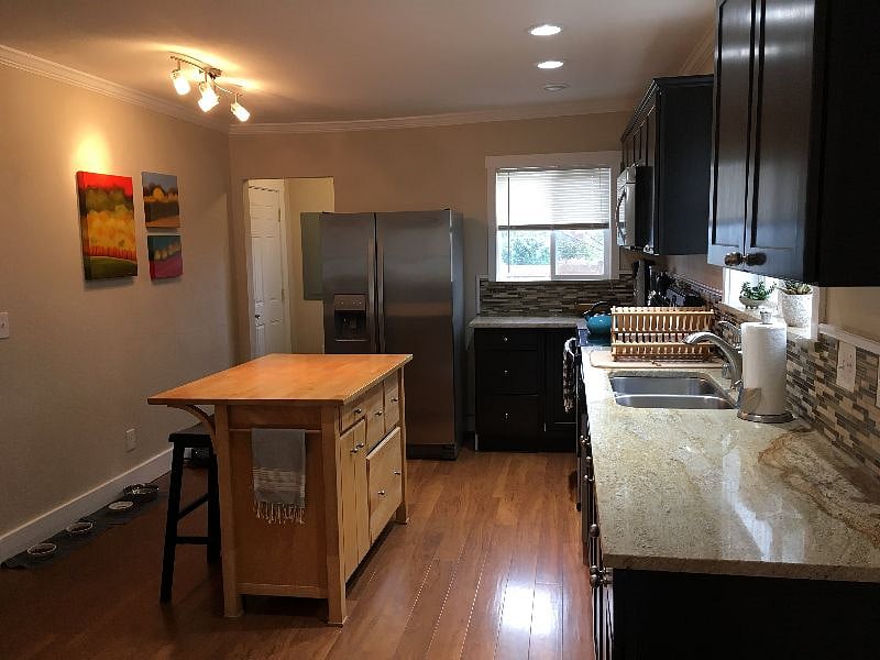 Kitchen has updated appliances and an island with stools. 