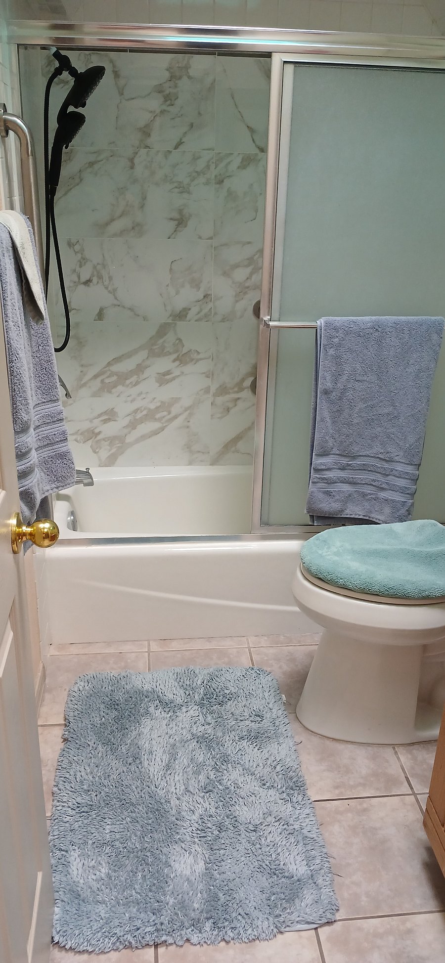 Remodeled bathroom with a marble tile and new shower head.  All towels and washcloths are furnished as well as lavish floor rugs as you enter the shower with new shower head.