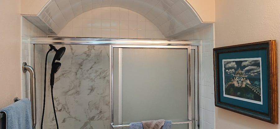 Full-sized shower and tub newly remodeled with tile surround and new modern toilet and sky light to brighten throughout and large mirror with vanity lights.  All cleaning supplies included under the sink cabinet.
