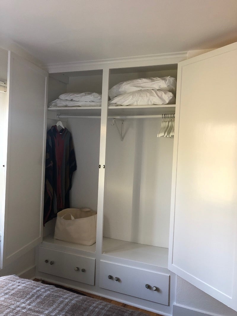 Large built in closet with extra bedding and pillows, slippers, robe and more storage below.