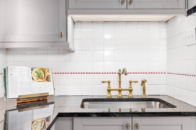 Vintage kitchen featuring preserved original wall tile and also new upgrades such as under cabinet lighting.