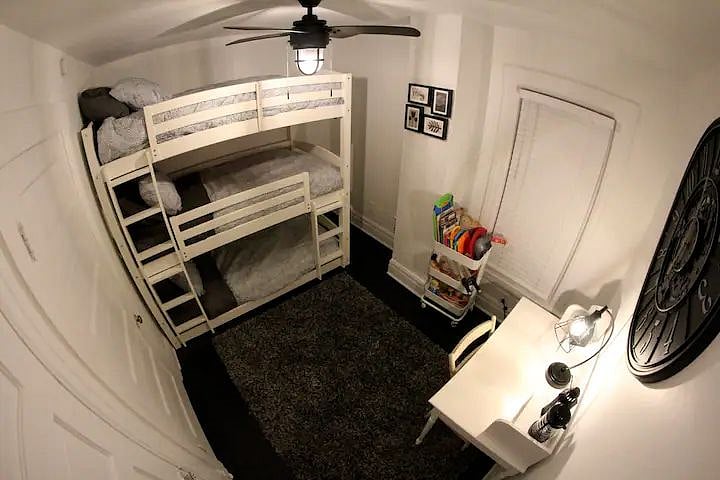 The smaller bedroom has a triple bunk bed, a rack filled with toys and a dedicated workspace.