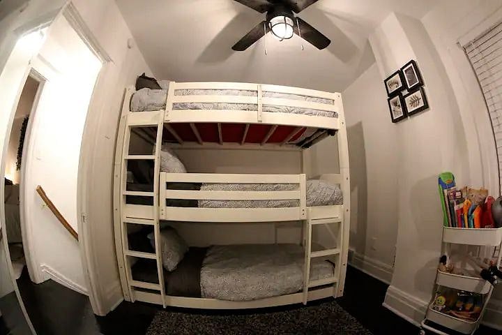 The smaller bedroom has a triple bunk bed, a rack filled with toys and a dedicated workspace.