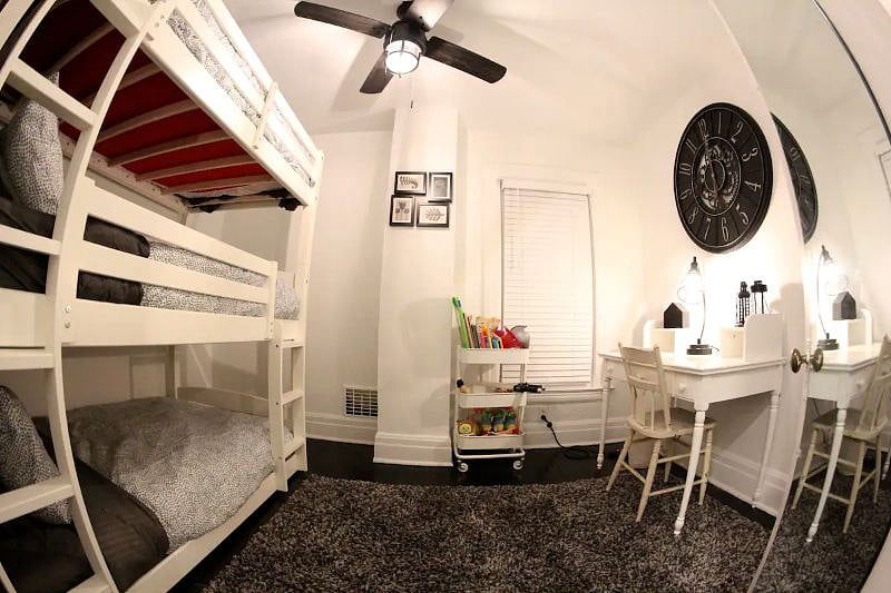 The smaller bedroom has a triple bunk bed, a rack filled with toys and a dedicated workspace.