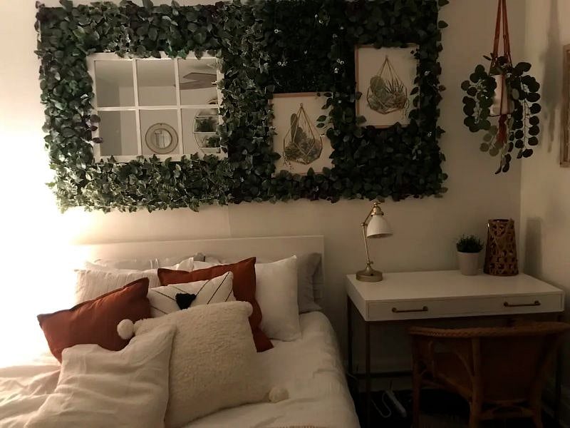 The larger bedroom is decorated in a boho chic style with verdant plant life and light, airy colors. It also has a dedicated workspace.