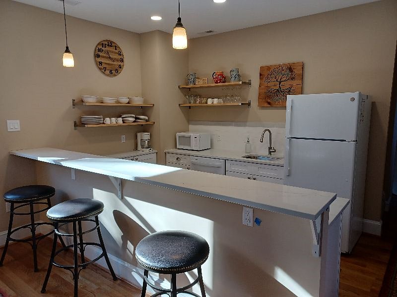 Open floor plan with bar stools and plenty of counter space. DIshes and everything you need to make your next meal! There is an induction cooktop and countertop oven/air fryer in the kitchenette (not visible in this photo).