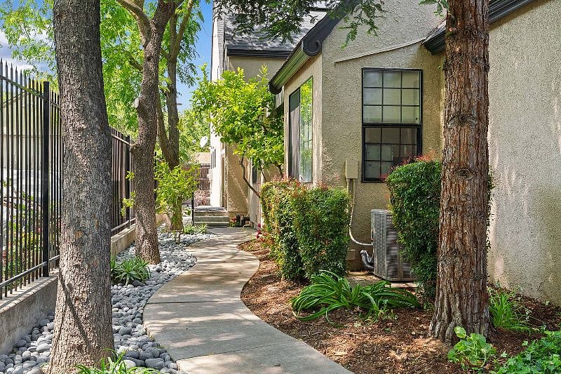 Walkway down the left side of the property leads to orange entrance door.