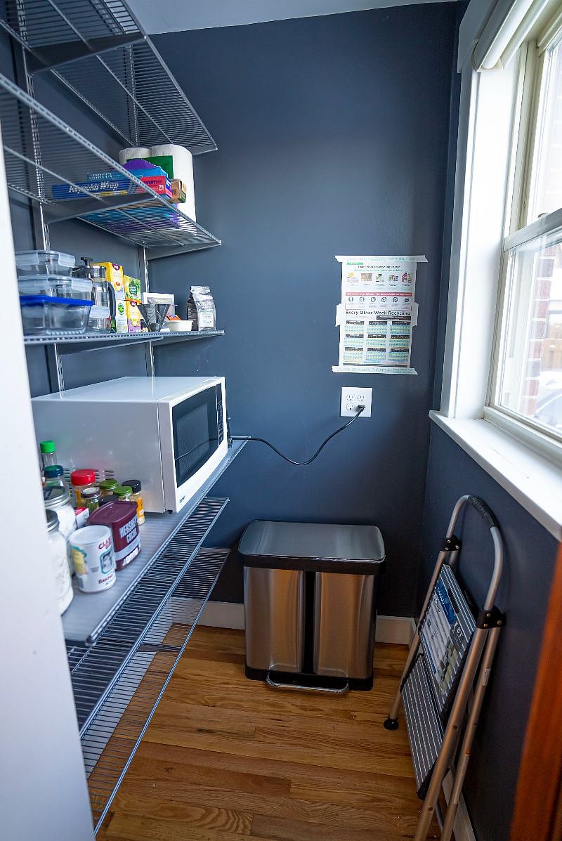 Pantry off of kitchen with microwave, trash, lots of shelving for pantry items