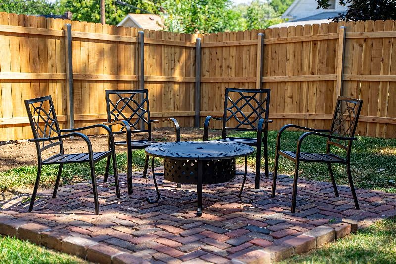 Newly fenced-in backyard with firepit and chairs