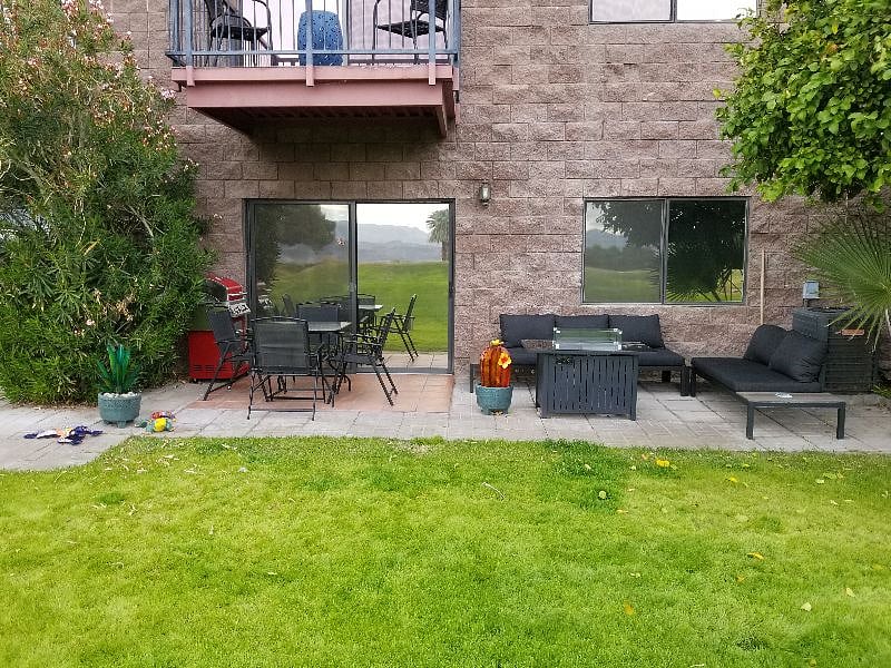 Huge back patio area with table and chair for outdoor dining, large l-shaped couch, and electric fireplace.