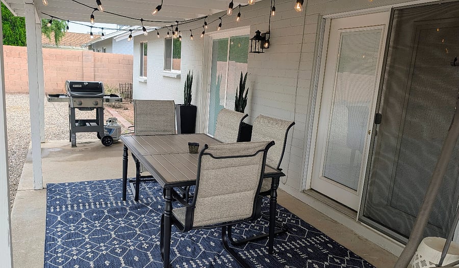 Covered patio with outdoor dining, BBQ grill, and fully fenced backyard.