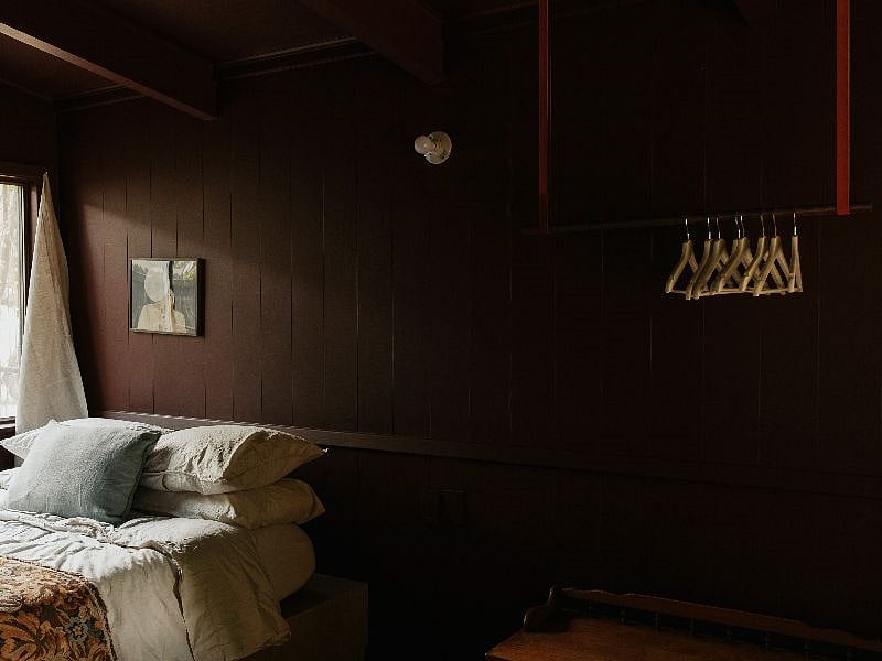 Our front bedroom features a built-in queen-sized bed, open closet storage, moody walls, and art.