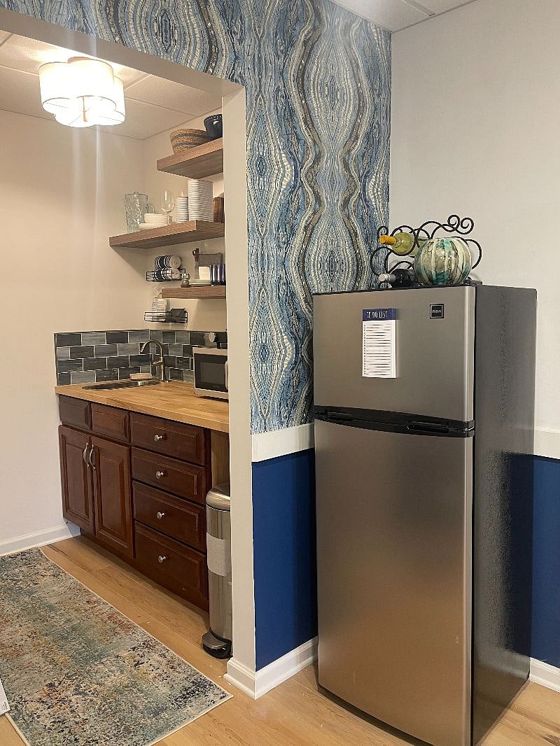View into kitchenette - apartment sized fridge with a separate freezer (and a wine rack on top)