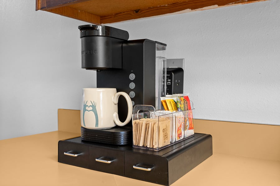 The coffee station is fully loaded with sugar, tea, and hot cocoaplus to-go coffee cups for mornings on the move.