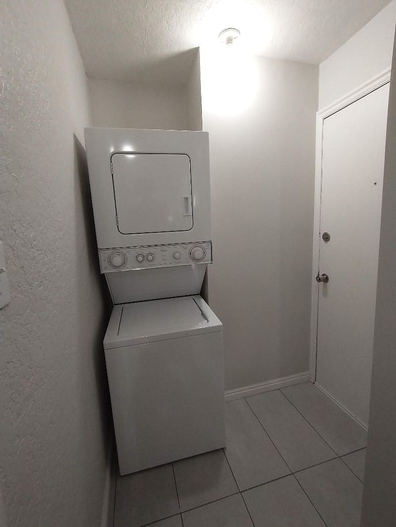 Photo inside shared laundry room. The door to the right of the laundry machine leads to the outside and is accessible via smartlock