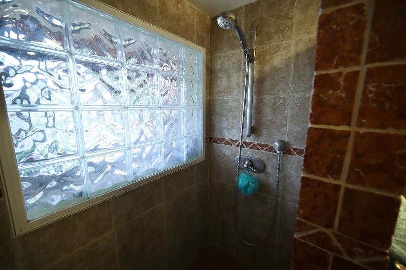 Walk in shower featuring designer stone tiles.