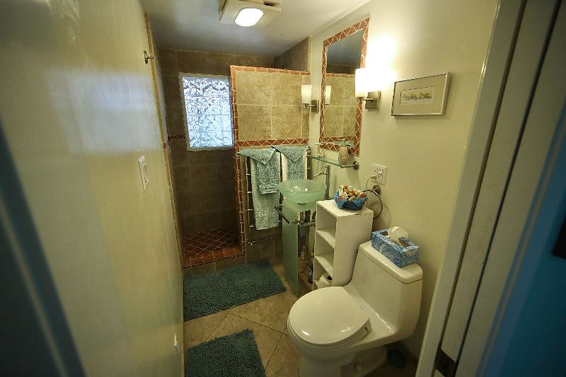 Private bathroom with designer stone tile work and raised art glass pedestal sink. Wall mounted heated towel warmer.