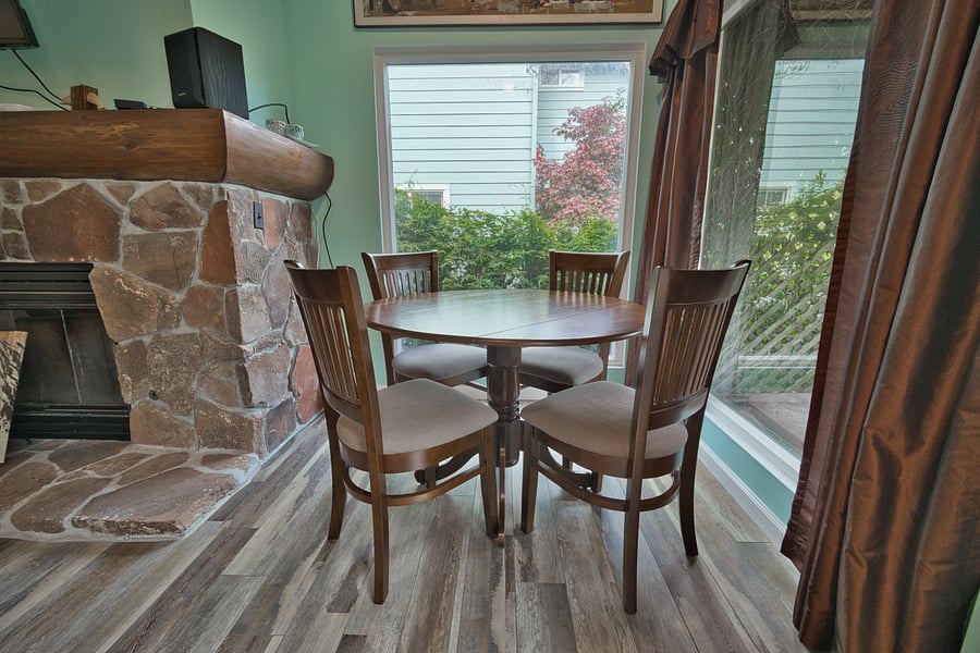 Main room featuring dining area next to picture windows and art stone fireplace. (Note fireplace is non-operational).
