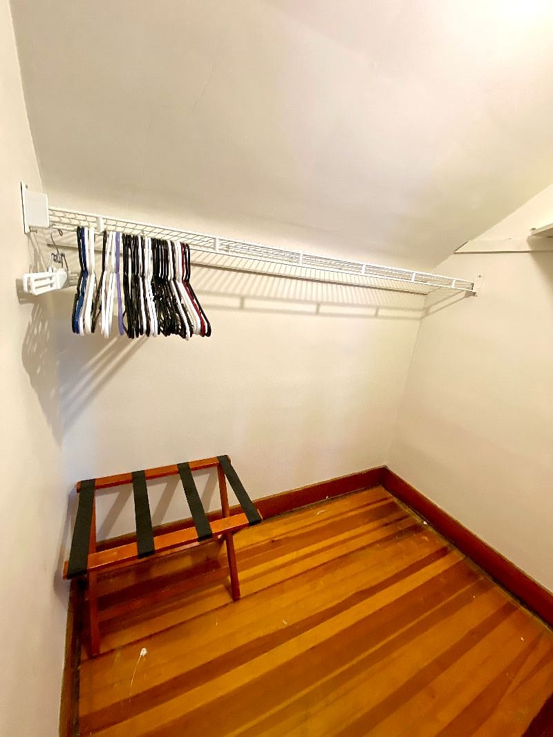 Bedroom with queen bed, blackout curtains, dresser and walk in closet.
