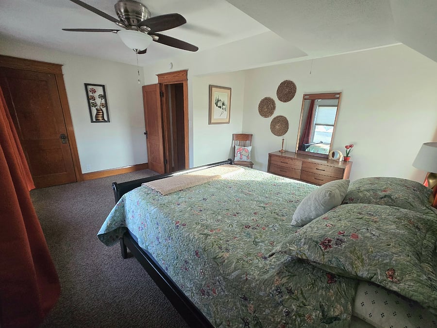 Bedroom with queen bed, blackout curtains, dresser and walk in closet.