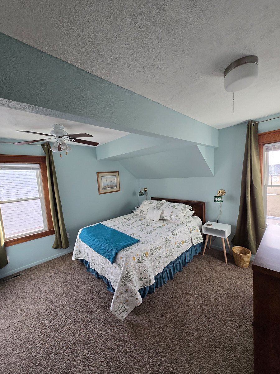 Bedroom with queen sized bed, blackout curtains, closet and dresser