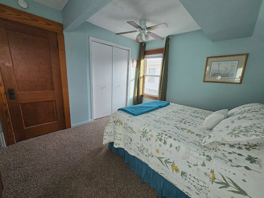 Bedroom with queen sized bed, blackout curtains, closet and dresser