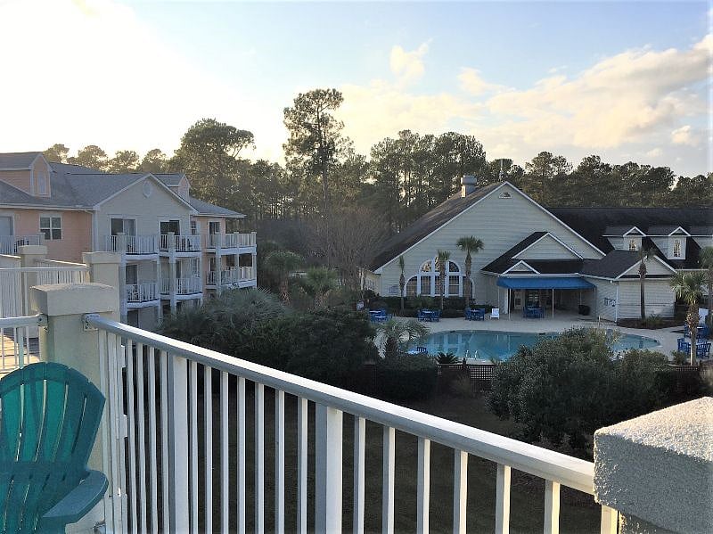 Private balcony view of pool and lawn with picnic and grills.