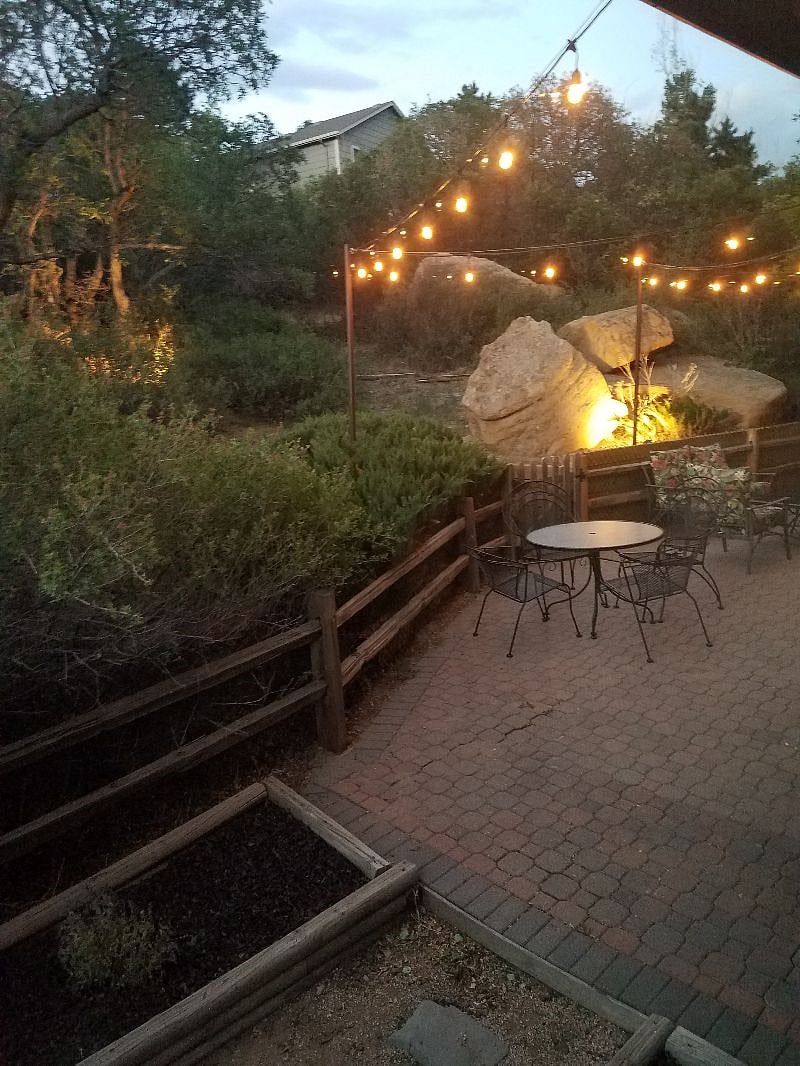 Boulder filled lit up back yard and patio