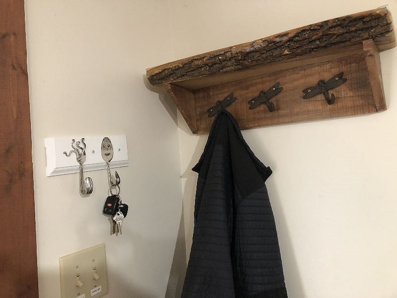 whimsical handmade key and coat rack in entry with small storage cabinet