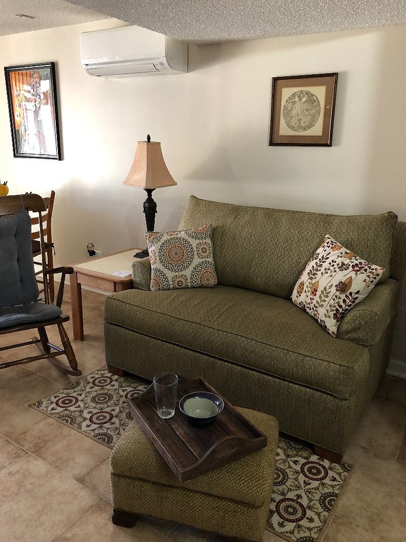 Comfortable lounge area with loveseat, ottoman, antique rocking chair, side table and lamp