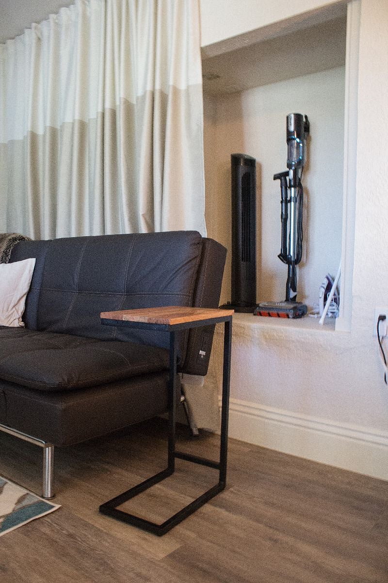 Storage behind sofa for vacuum, ironing board and suitcases.