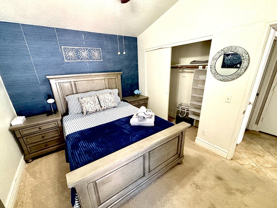 This welcoming bedroom includes a queen bed, television, dresser, and closet space.