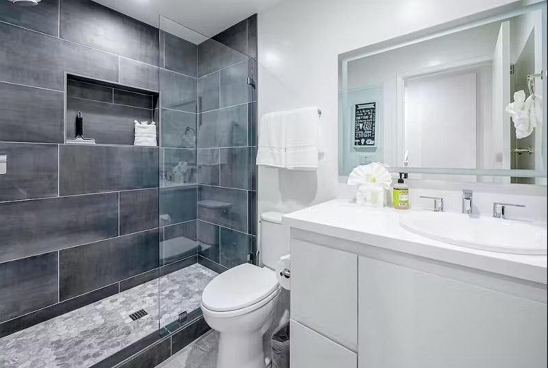 Bathroom includes backlit mirror with anti-fog, as well as a Bluetooth shower speaker