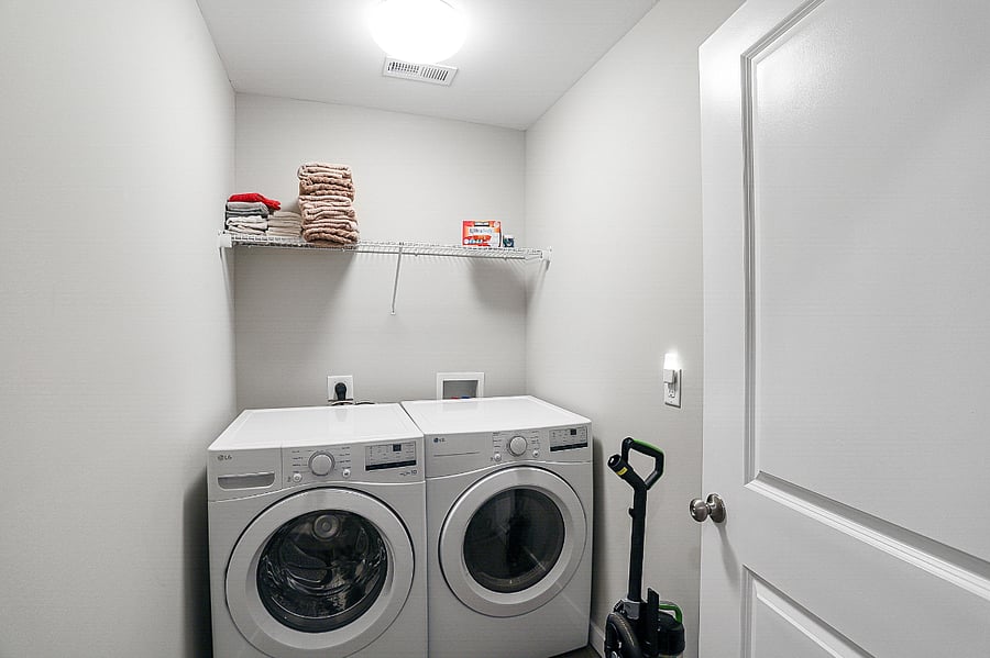 Full sized laundry room with storage & HE front load washer and dryer.