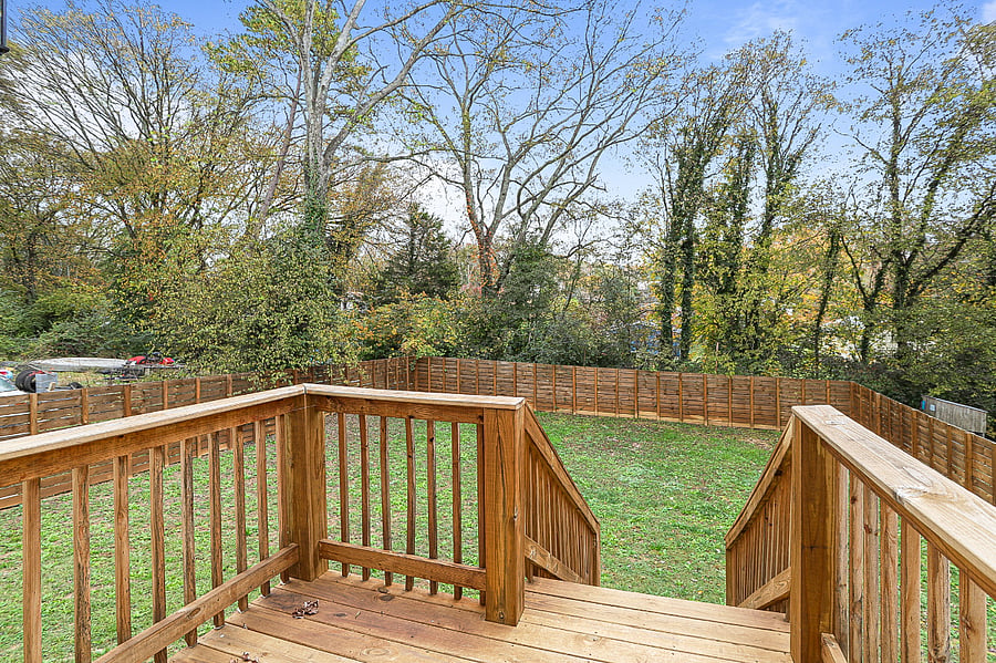 Rear deck off primary bedroom with stairs that lead down to the fully fenced in back yard.
