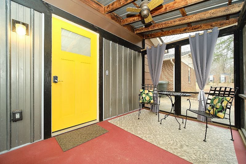 Screened in porch with patio furniture and privacy curtains. The front door is equipped with keypad entry.