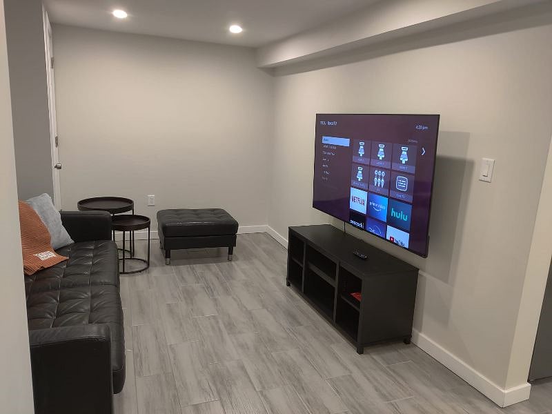 Cozy living room space with leather couch, ottoman and TV