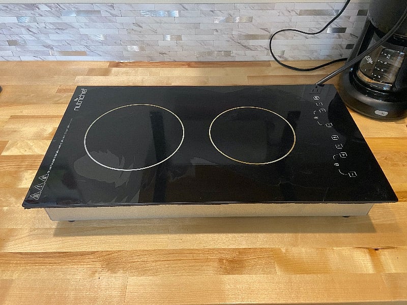 Two burner cook top is stored under cabinet for counter space