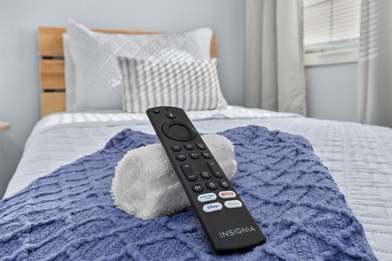 Relaxing guest bedroom with two comfortable twin-size beds, alarm clock, 32-in smart tv, closet with storage, and ceiling fan