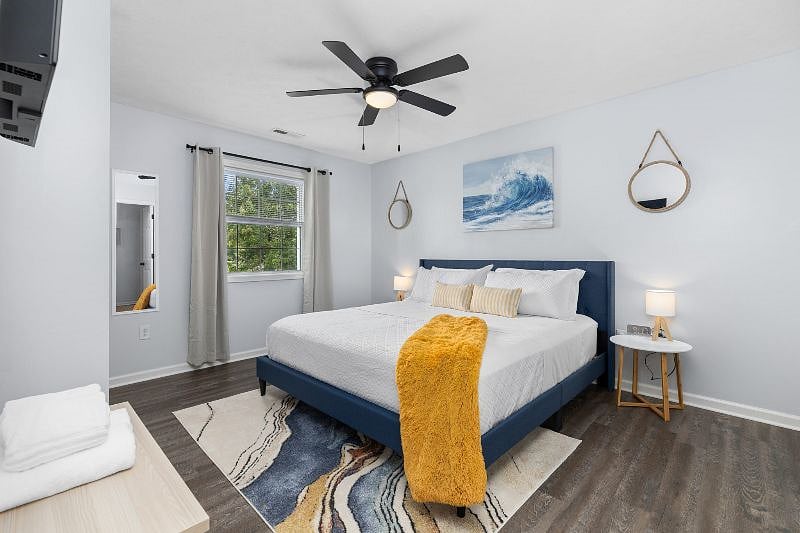 Warm and inviting main bedroom with a comfortable king-size bed, alarm clock, 32-in smart tv, closet with storage, and ceiling fan